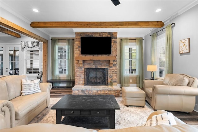 living area with ornamental molding, beamed ceiling, a fireplace, and wood finished floors