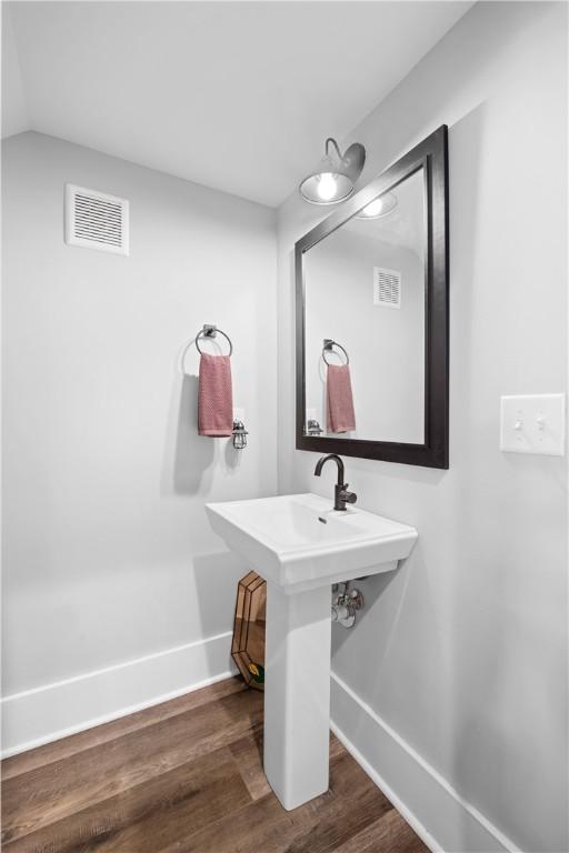 bathroom featuring baseboards, visible vents, vaulted ceiling, and wood finished floors