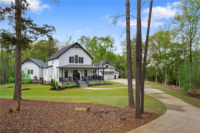 modern farmhouse featuring an attached garage, a front lawn, board and batten siding, driveway, and covered porch