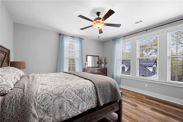 bedroom featuring baseboards, visible vents, wood finished floors, and a ceiling fan