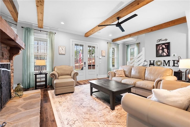 living room featuring wood finished floors, a stone fireplace, beamed ceiling, ceiling fan, and recessed lighting