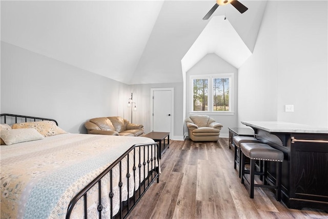 bedroom with baseboards, ceiling fan, wood finished floors, and vaulted ceiling