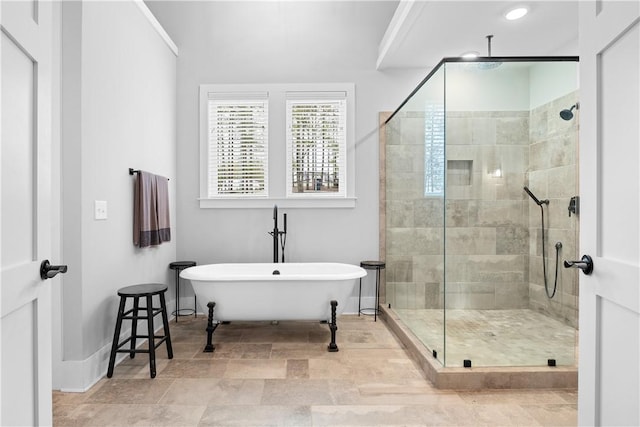 bathroom featuring a freestanding tub, baseboards, and a shower stall