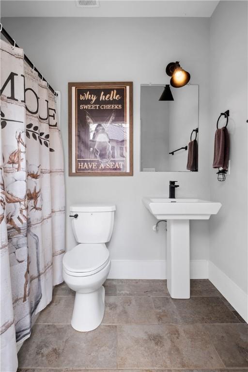 bathroom with a shower with curtain, toilet, baseboards, a sink, and visible vents