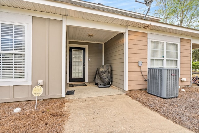 entrance to property featuring board and batten siding and cooling unit