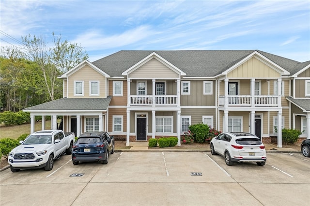 multi unit property with roof with shingles, board and batten siding, and uncovered parking