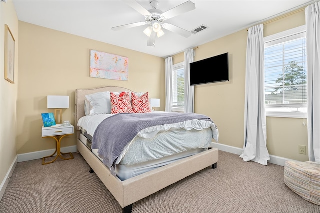 carpeted bedroom with baseboards, multiple windows, a ceiling fan, and visible vents