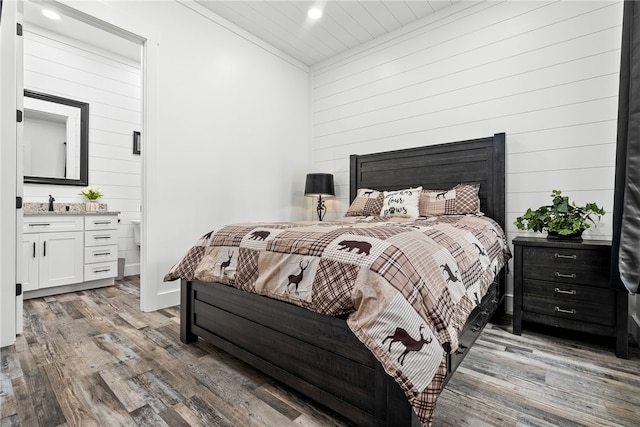 bedroom with ensuite bath, wood walls, and hardwood / wood-style flooring