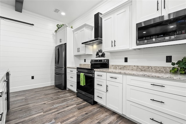 kitchen featuring white cabinetry, light stone counters, wall chimney range hood, and appliances with stainless steel finishes