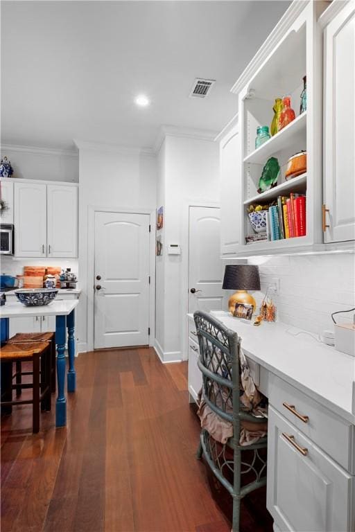 interior space with backsplash, white cabinets, and a breakfast bar area