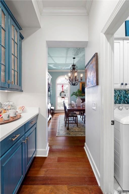 hallway featuring a chandelier, washer / dryer, ornamental molding, and dark wood-type flooring