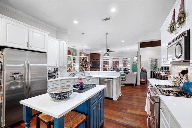 kitchen with ceiling fan, appliances with stainless steel finishes, decorative light fixtures, a kitchen bar, and white cabinetry