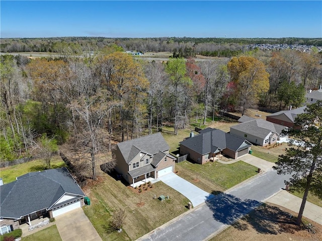 drone / aerial view featuring a wooded view and a residential view