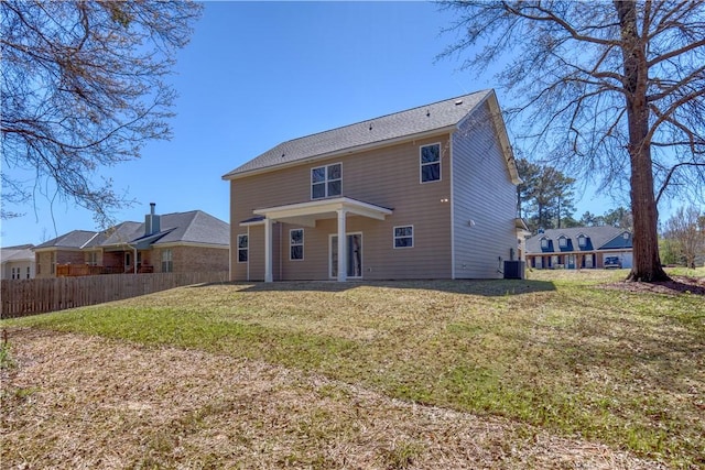 rear view of house featuring central air condition unit, fence, and a lawn
