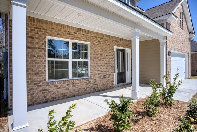 entrance to property featuring a garage and brick siding