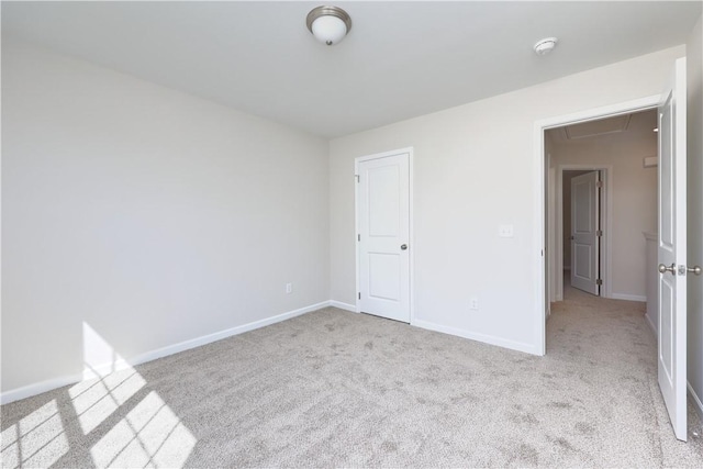 spare room featuring carpet flooring, baseboards, and attic access