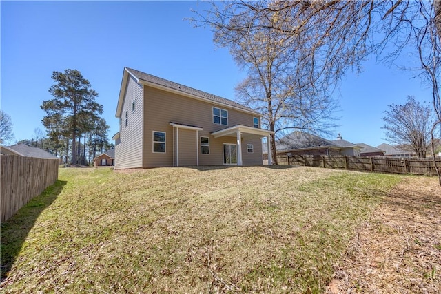 rear view of house featuring a fenced backyard and a lawn