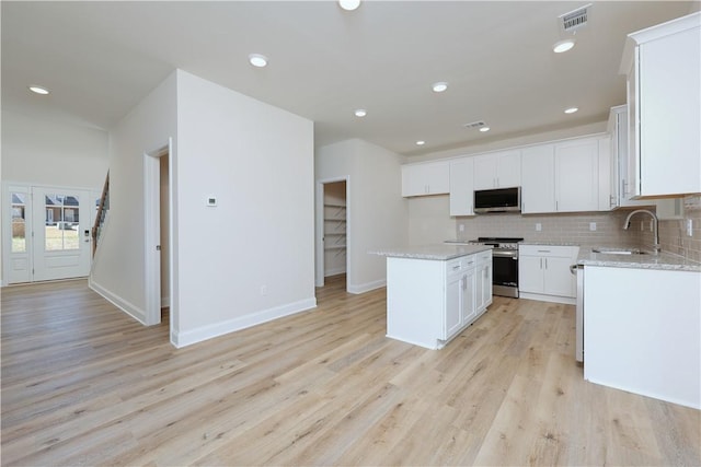 kitchen featuring light wood-type flooring, a sink, visible vents, and stainless steel appliances