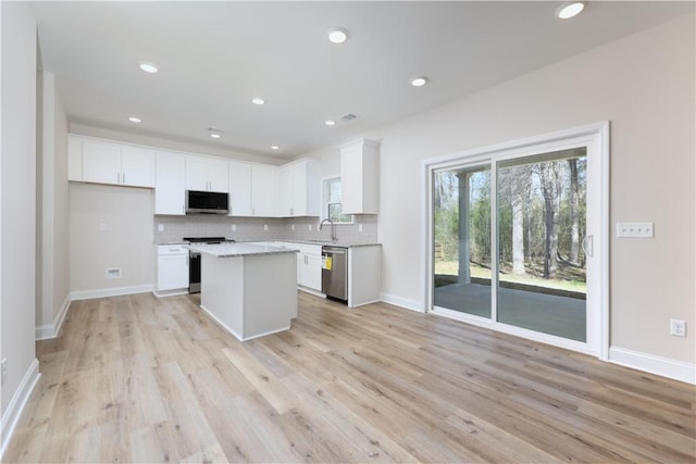 kitchen featuring a center island, a sink, appliances with stainless steel finishes, white cabinetry, and backsplash