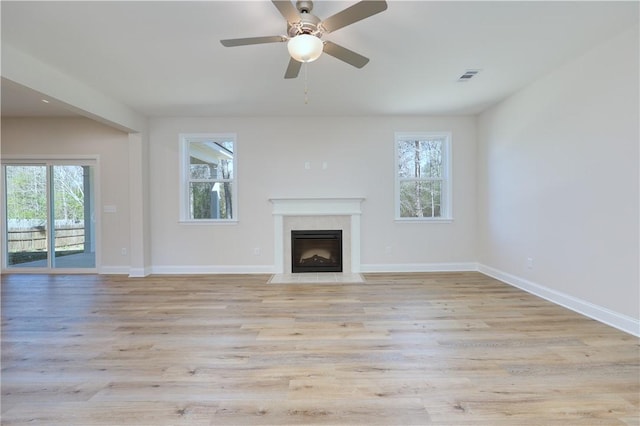 unfurnished living room with a fireplace with flush hearth, a healthy amount of sunlight, and visible vents