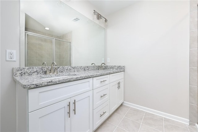 full bath with visible vents, a sink, a stall shower, double vanity, and baseboards