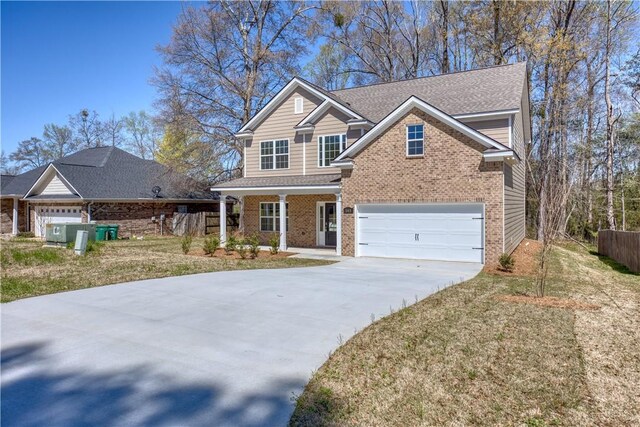 traditional-style house featuring a garage, fence, a front lawn, brick siding, and driveway