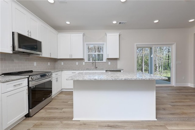 kitchen with visible vents, white cabinets, a sink, appliances with stainless steel finishes, and a kitchen island