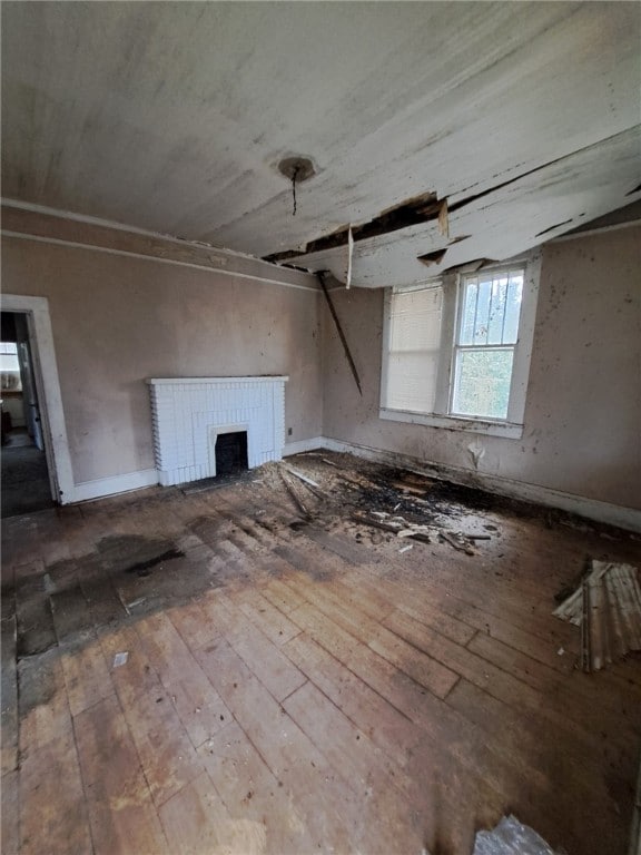 unfurnished living room featuring hardwood / wood-style flooring and a brick fireplace