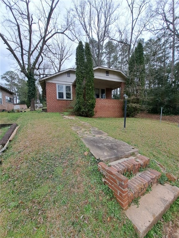 view of front of house with brick siding, a front lawn, and a carport