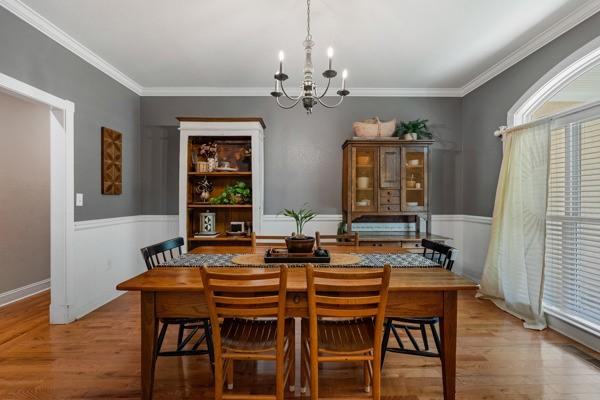 dining area with light wood-type flooring, an inviting chandelier, and ornamental molding