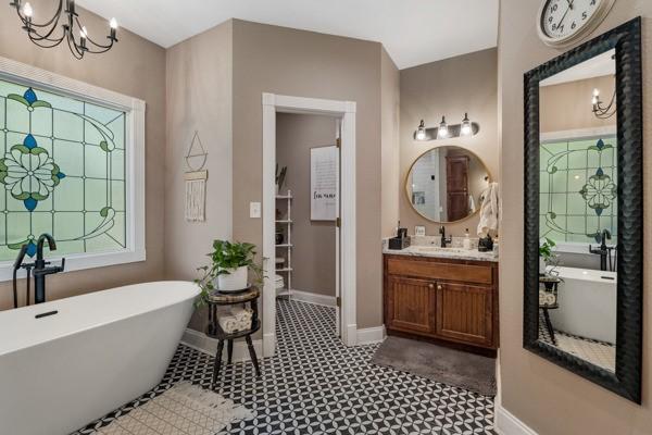 bathroom with vanity, a bathing tub, and a notable chandelier