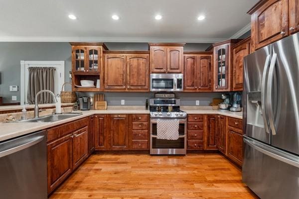 kitchen featuring crown molding, sink, light hardwood / wood-style floors, and appliances with stainless steel finishes