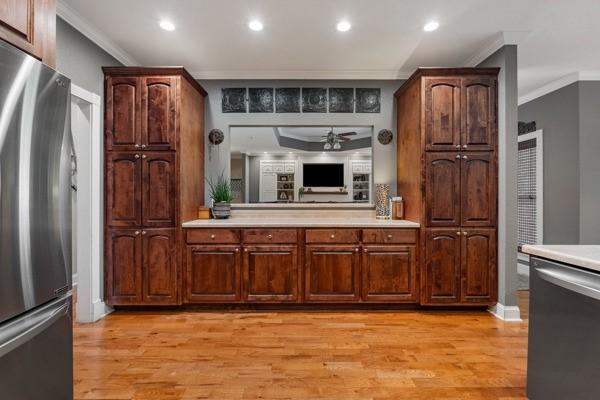 kitchen featuring light wood-type flooring, stainless steel appliances, ceiling fan, and crown molding