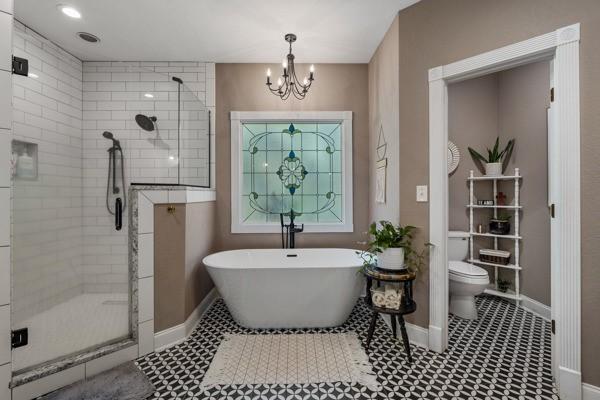 bathroom featuring independent shower and bath, a chandelier, and toilet