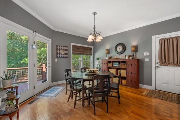 dining space with an inviting chandelier, ornamental molding, and hardwood / wood-style flooring