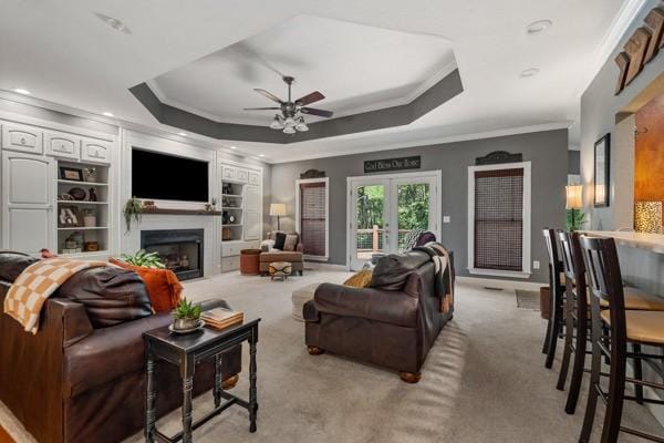 carpeted living room featuring ceiling fan, a raised ceiling, crown molding, and french doors