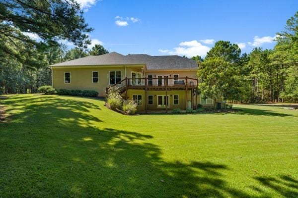 rear view of property with a wooden deck and a lawn