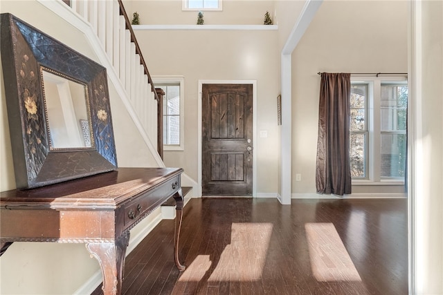 entryway with a healthy amount of sunlight, stairs, and dark wood-type flooring