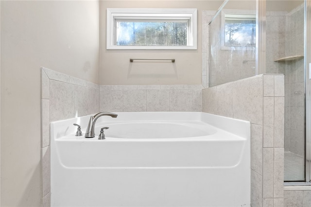 bathroom featuring a stall shower and a bath