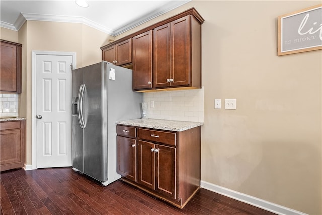 kitchen with light stone counters, dark wood finished floors, ornamental molding, stainless steel fridge, and baseboards