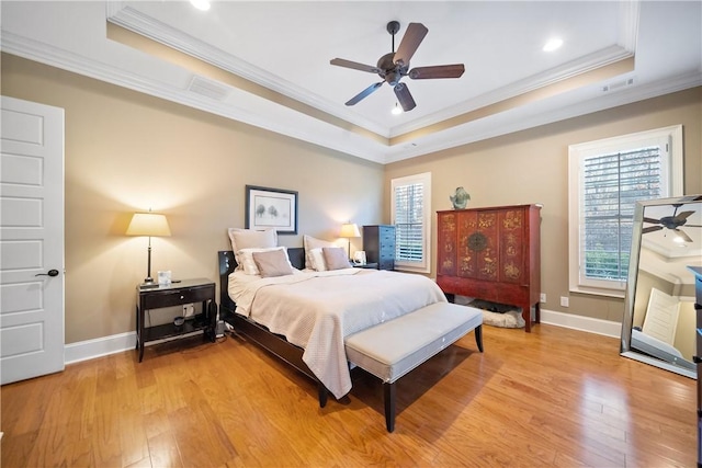 bedroom with light hardwood / wood-style floors and a tray ceiling