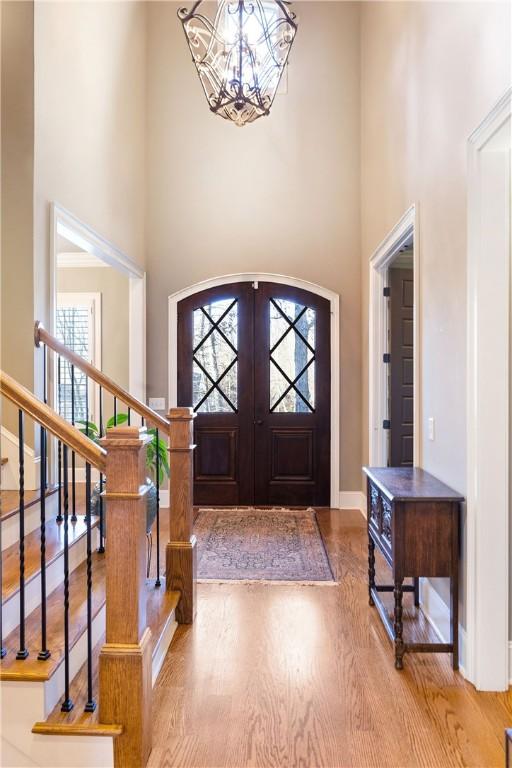 entrance foyer with a high ceiling, hardwood / wood-style floors, a notable chandelier, and french doors