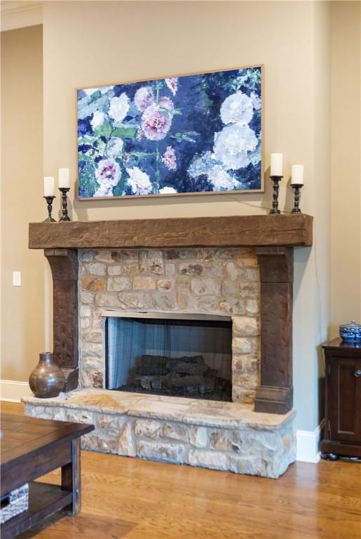 details featuring crown molding, a stone fireplace, and hardwood / wood-style flooring