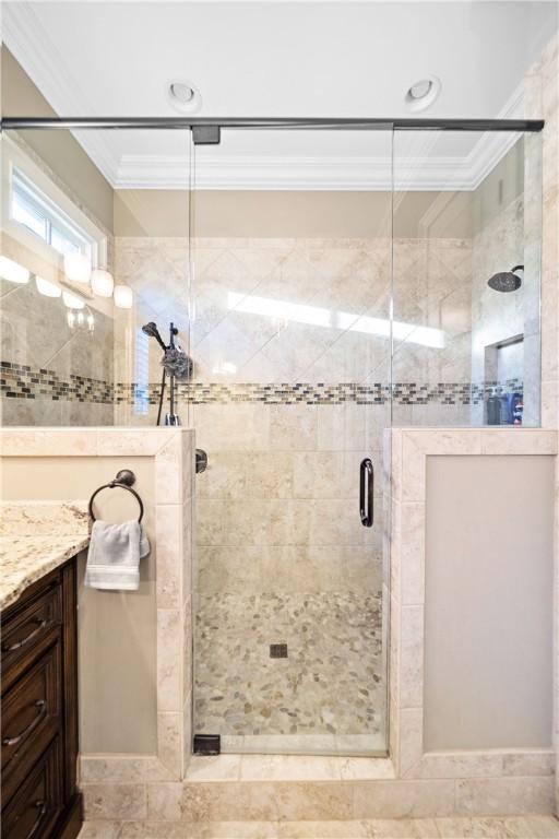 bathroom featuring ornamental molding, a shower with door, and vanity