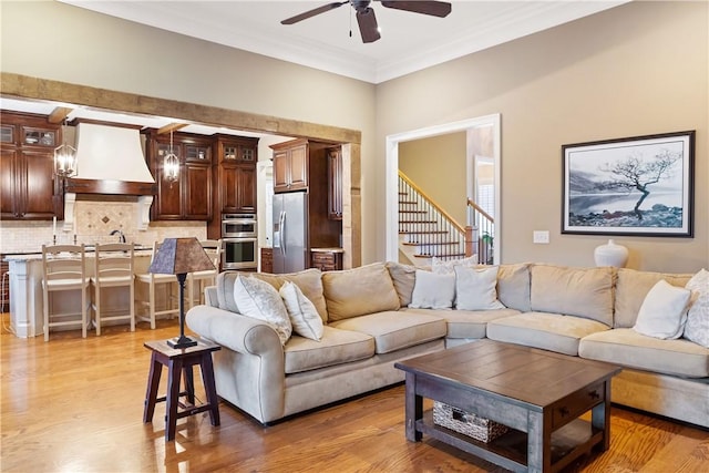 living room with ceiling fan, ornamental molding, sink, and light hardwood / wood-style floors