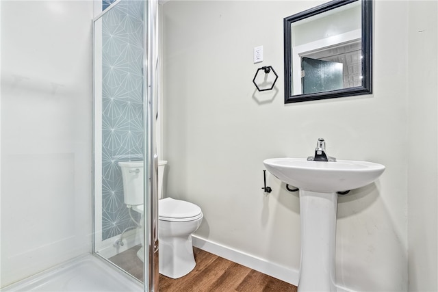 bathroom featuring toilet, a shower stall, wood finished floors, and baseboards