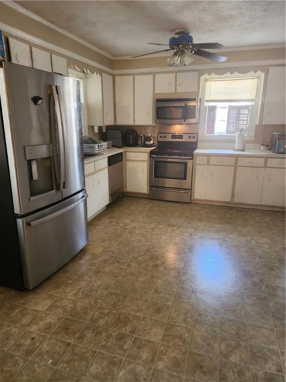 kitchen featuring ceiling fan, crown molding, stainless steel appliances, and a textured ceiling