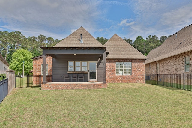 back of house featuring a shingled roof, a patio, a lawn, and a fenced backyard