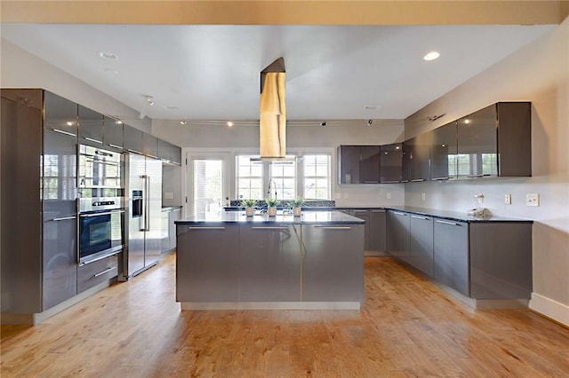 kitchen featuring a kitchen island, high quality fridge, dark countertops, and modern cabinets