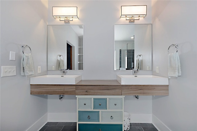 full bath featuring baseboards, tile patterned floors, double vanity, and a sink